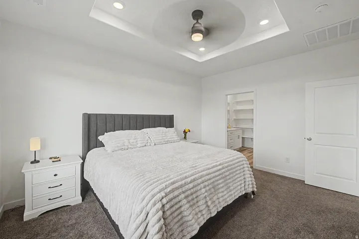 Bedroom featuring a tray ceiling with recessed lighting and a ceiling fan