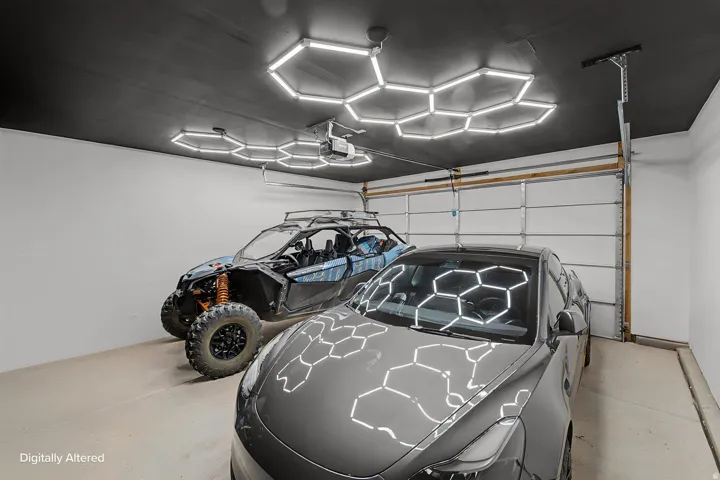 Two-car garage featuring a black ceiling with integrated hexagonal lighting, bright white walls, and a light-colored floor