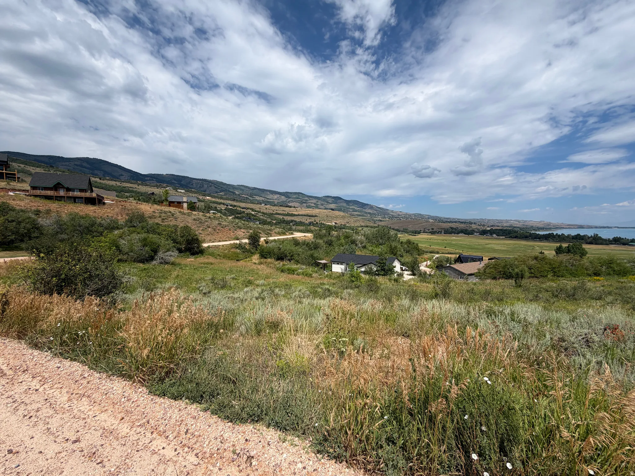 Expansive undeveloped land featuring varied terrain, natural vegetation, and distant mountain ranges with a visible body of water