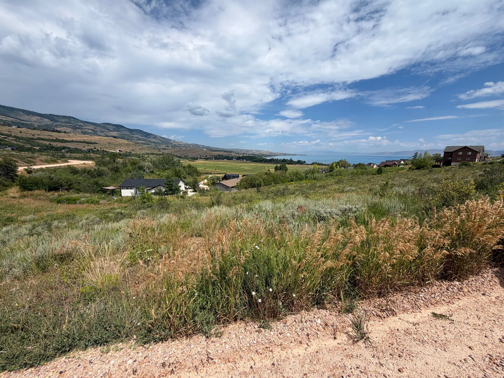 Expansive landscape featuring distant water, mountainous terrain, and natural vegetation
