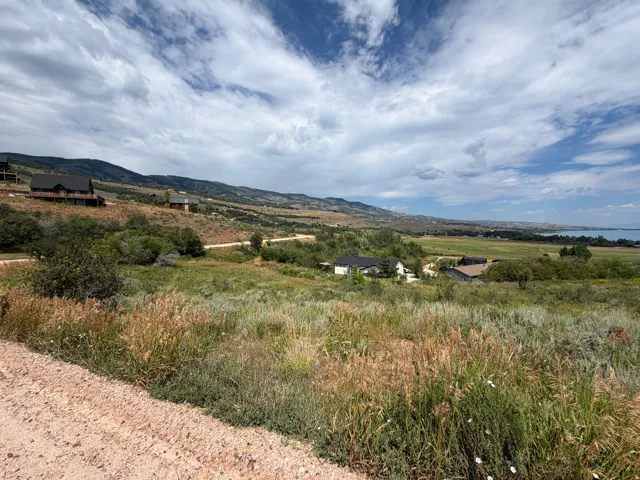 Expansive undeveloped land featuring varied terrain, natural vegetation, and distant mountain ranges with a visible body of water