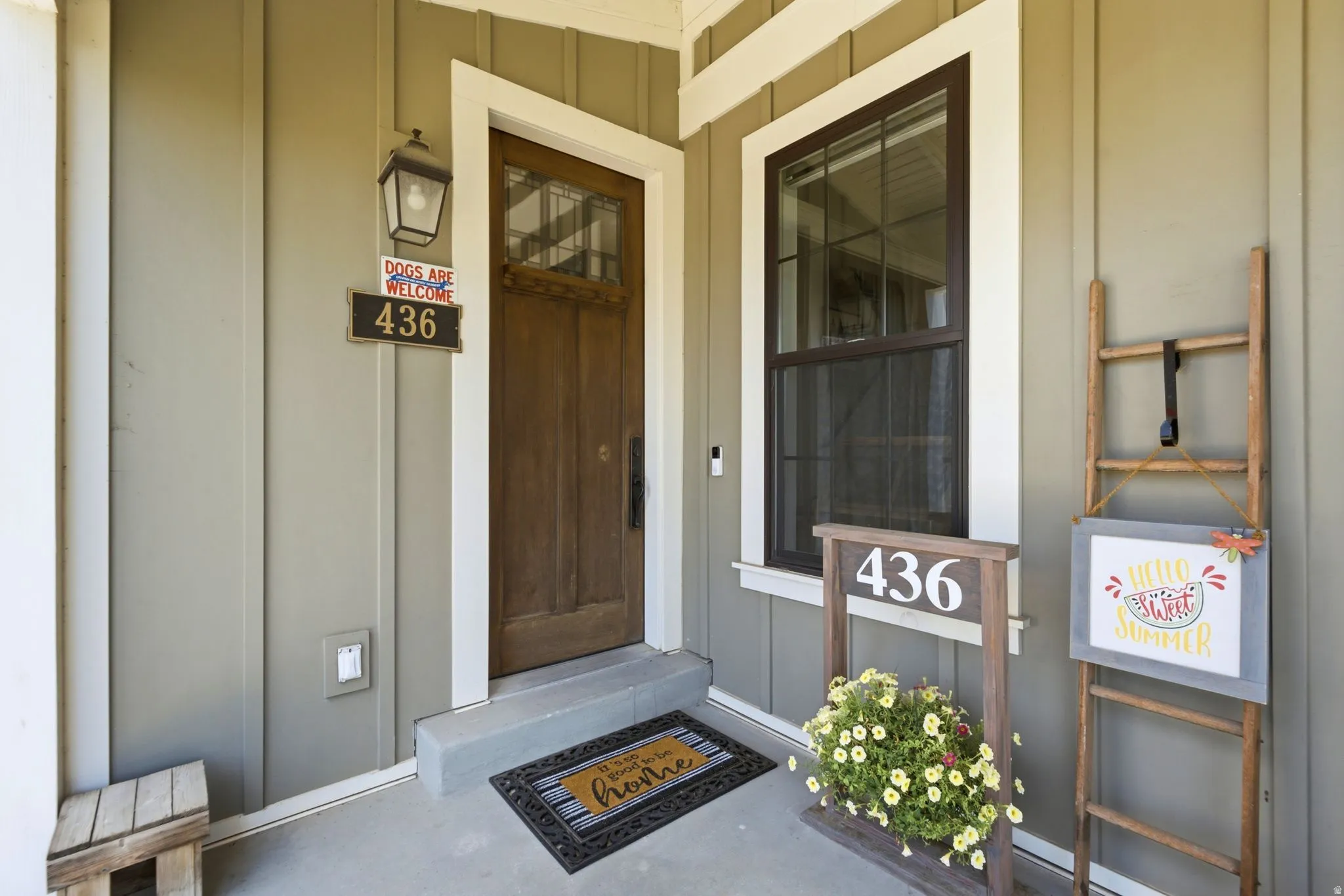 Inviting front entry featuring vertical siding, a solid wood door with upper glass panels, an exterior wall lantern