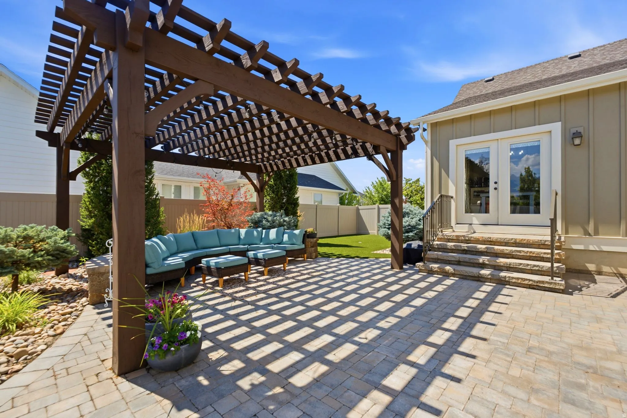Patio right off of the kitchen/dining  with paver patio featuring a large pergola, decorative pavers and artificial turf