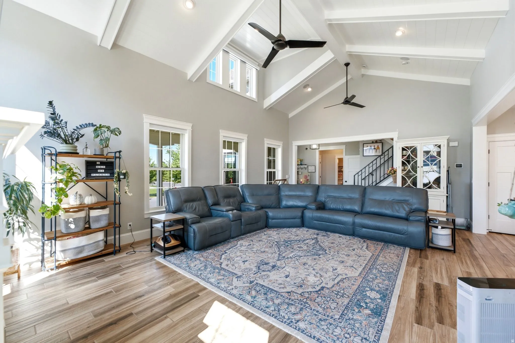 Spacious living area featuring vaulted ceilings with exposed beams, multiple windows providing ample natural light