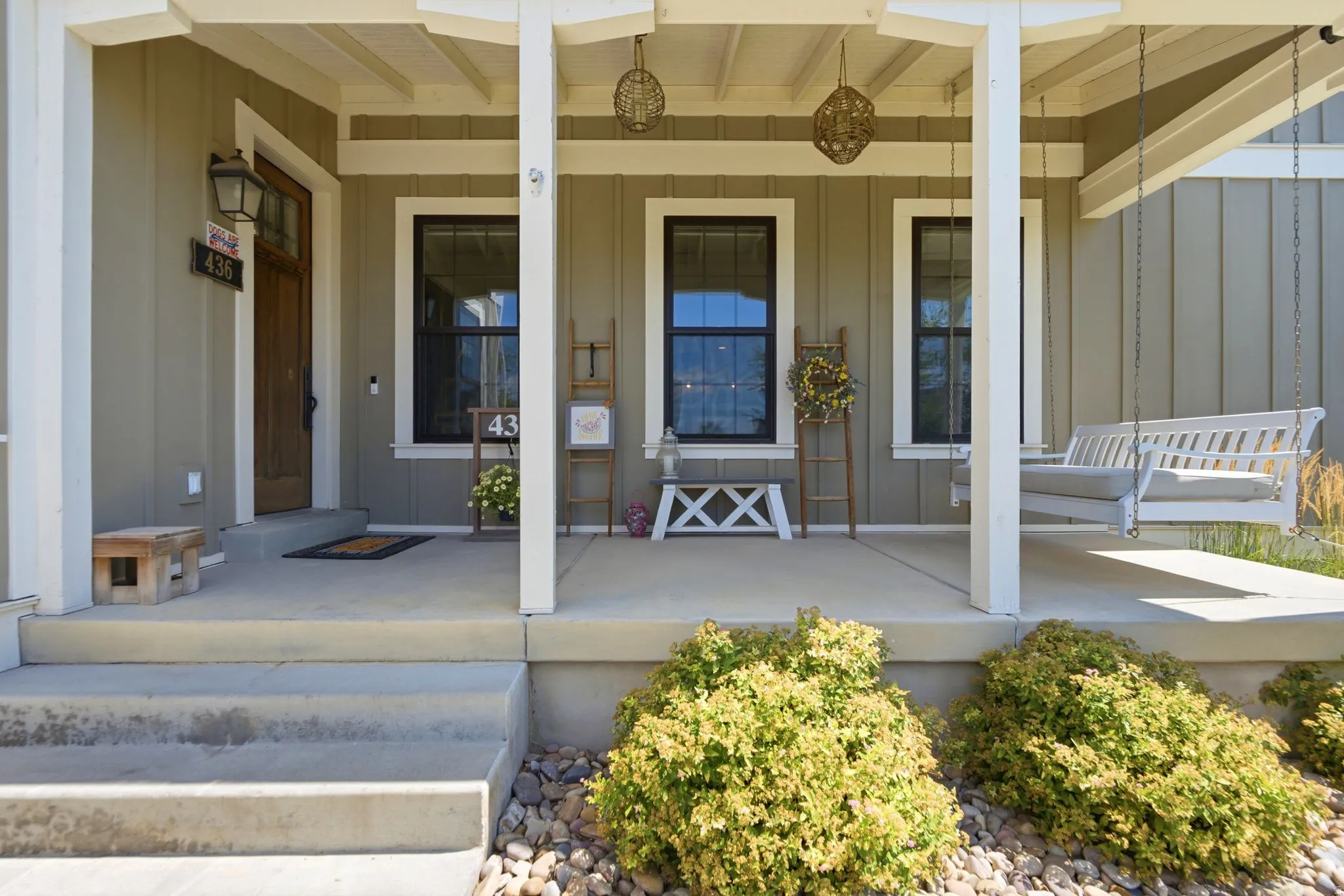 Inviting covered front porch with a wood-finish entry door and board-and-batten siding