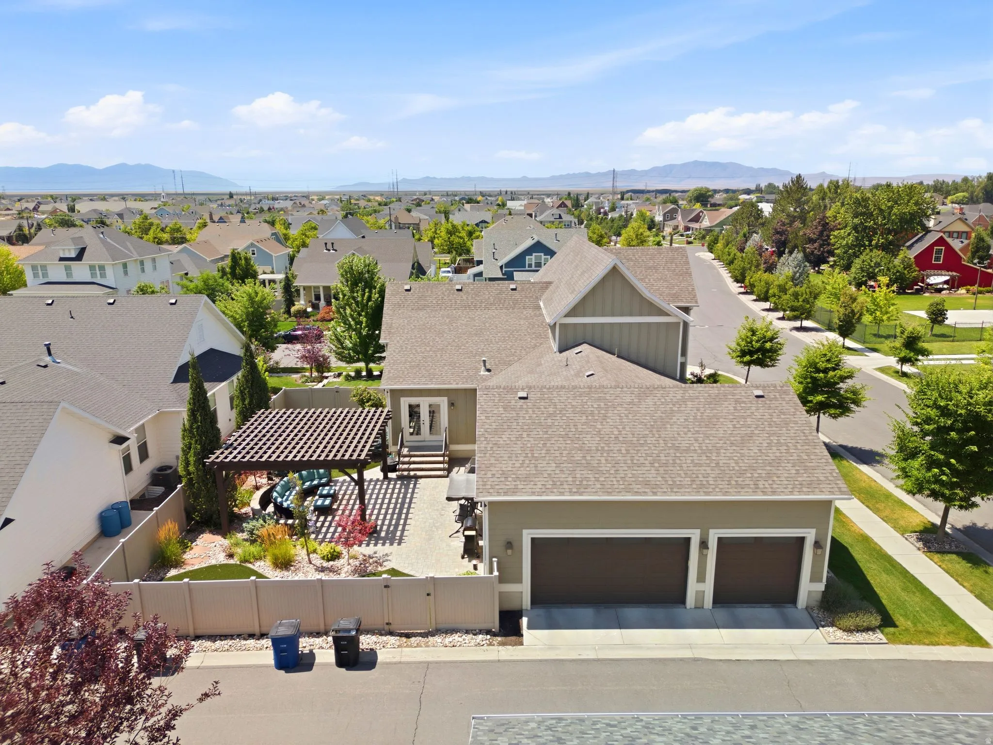 Expansive rear patio featuring a pergola and landscaped garden beds