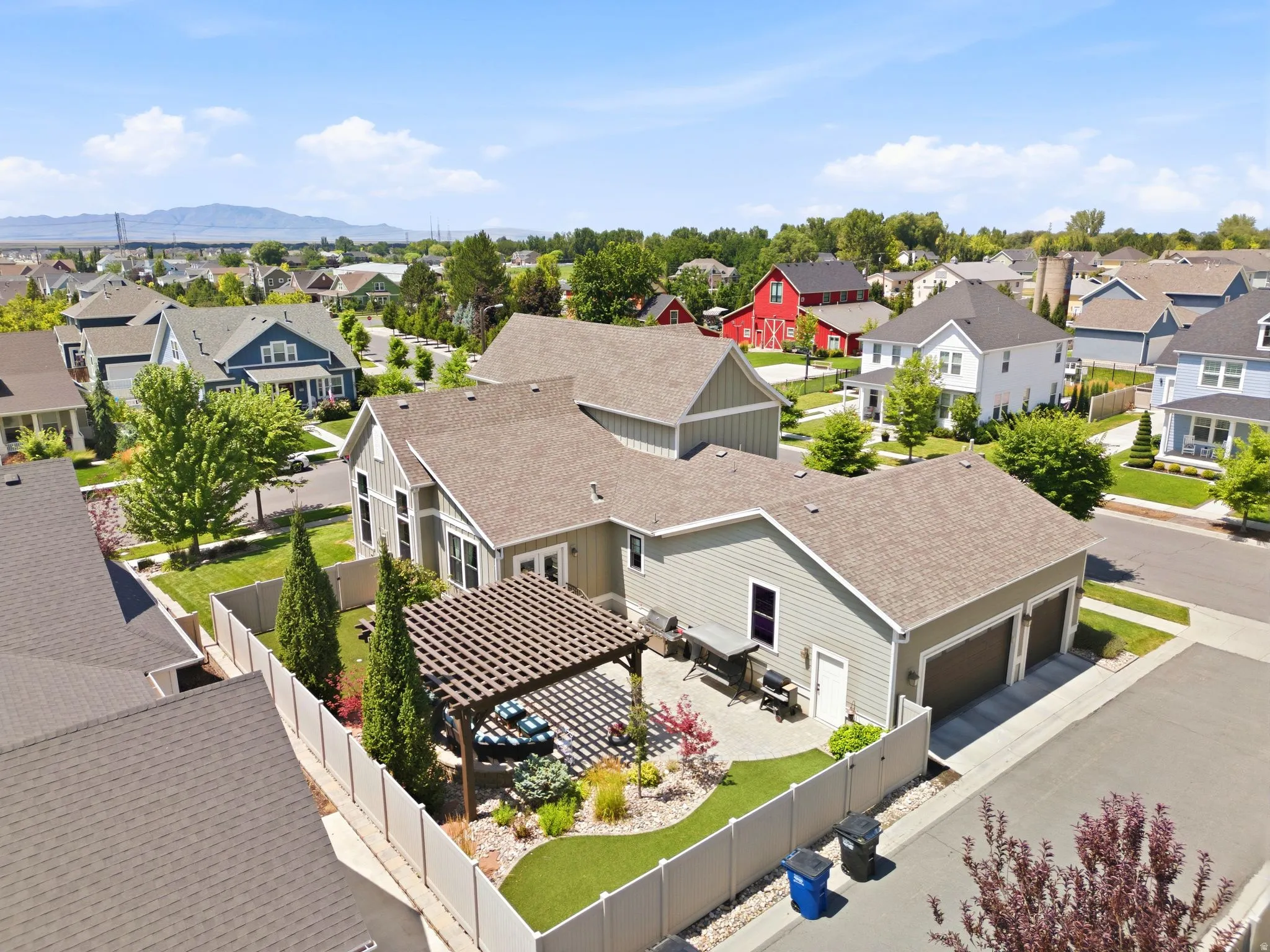 Aerial view of spacious backyard featuring a pergola-covered patio, manicured lawn, and mature landscaping