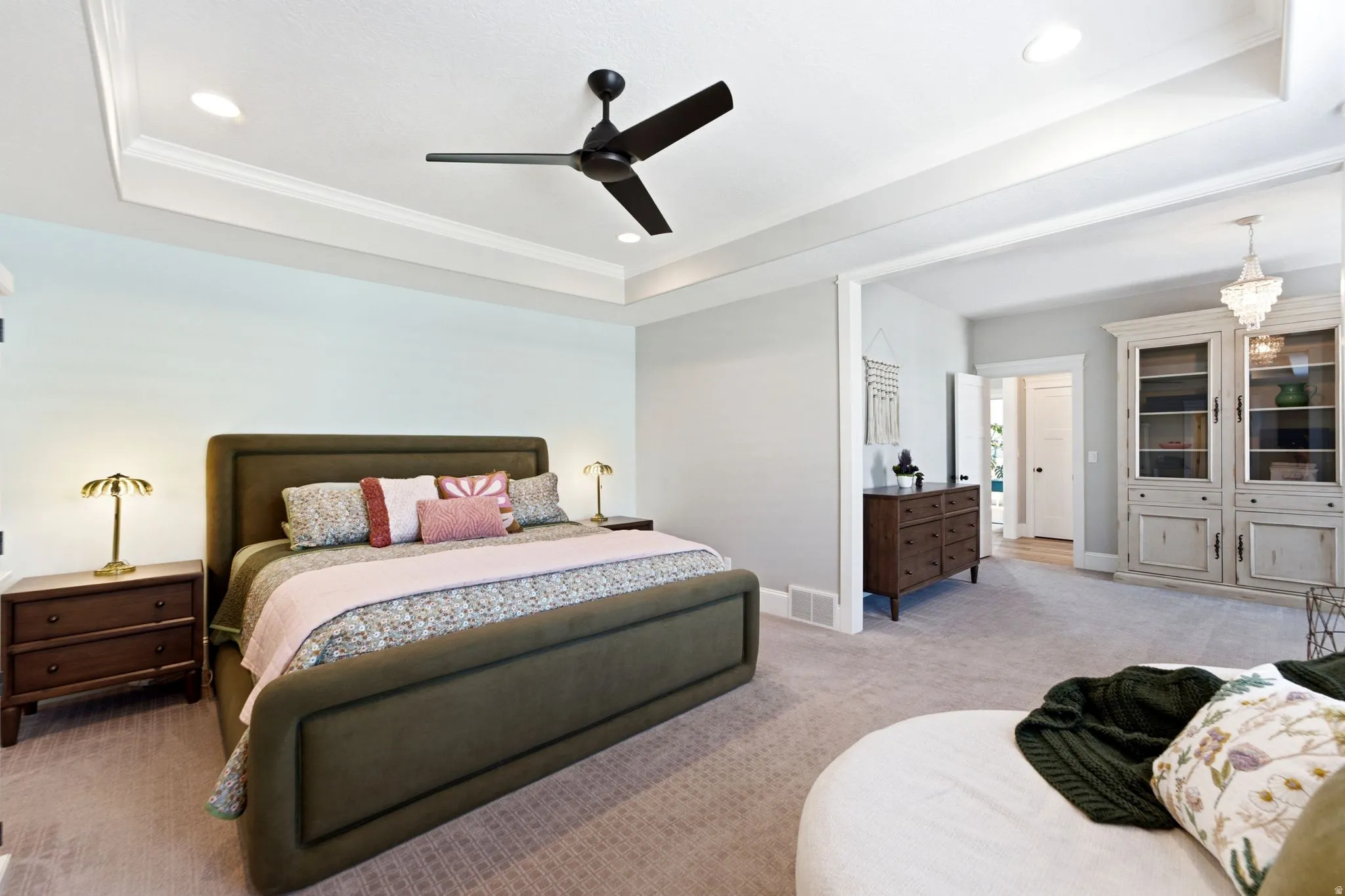 Primary suite featuring a tray ceiling with recessed lighting and seating area