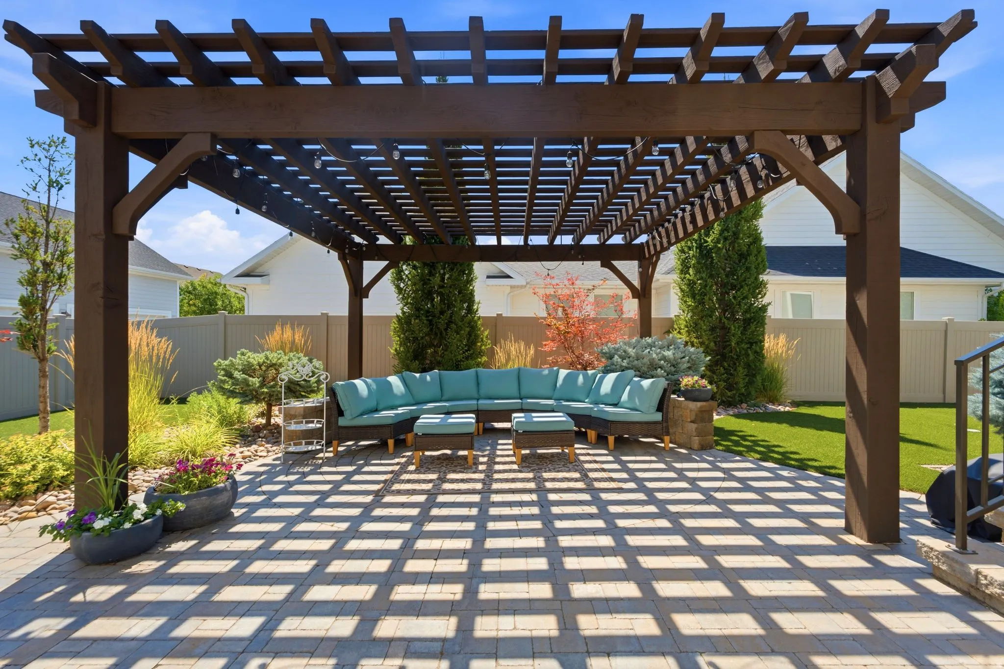 Expansive paver patio featuring a large pergola and artificial turf lawn