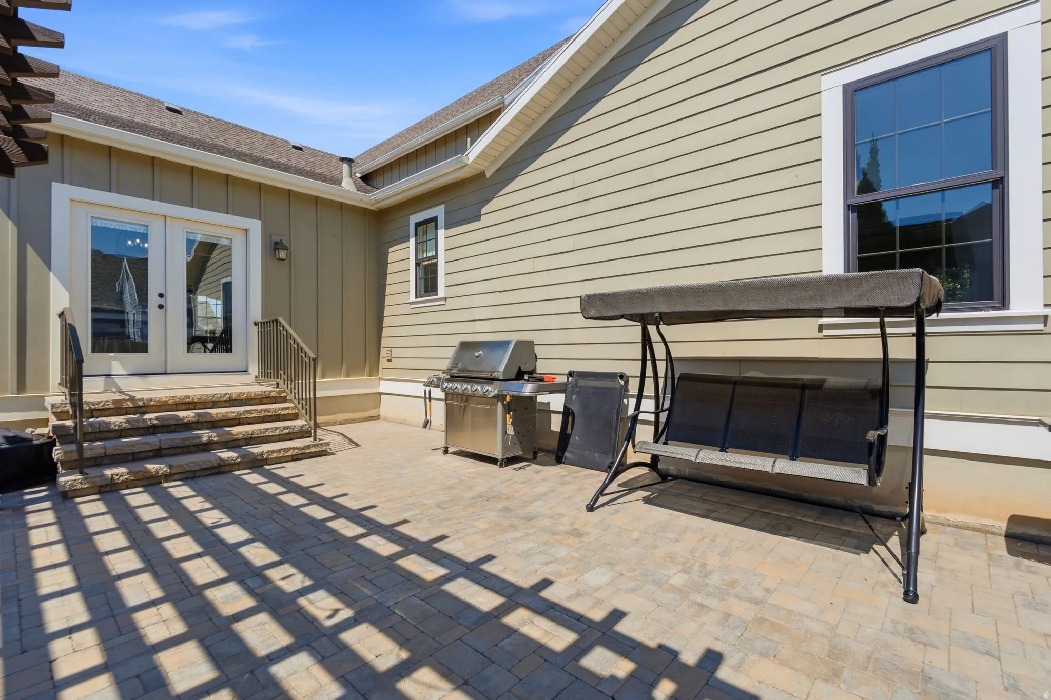 Paved patio area featuring stone steps with metal railings, double glass doors from the kitchen