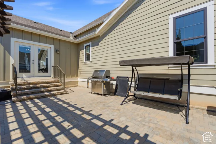 Paved patio area featuring stone steps with metal railings, double glass doors from the kitchen