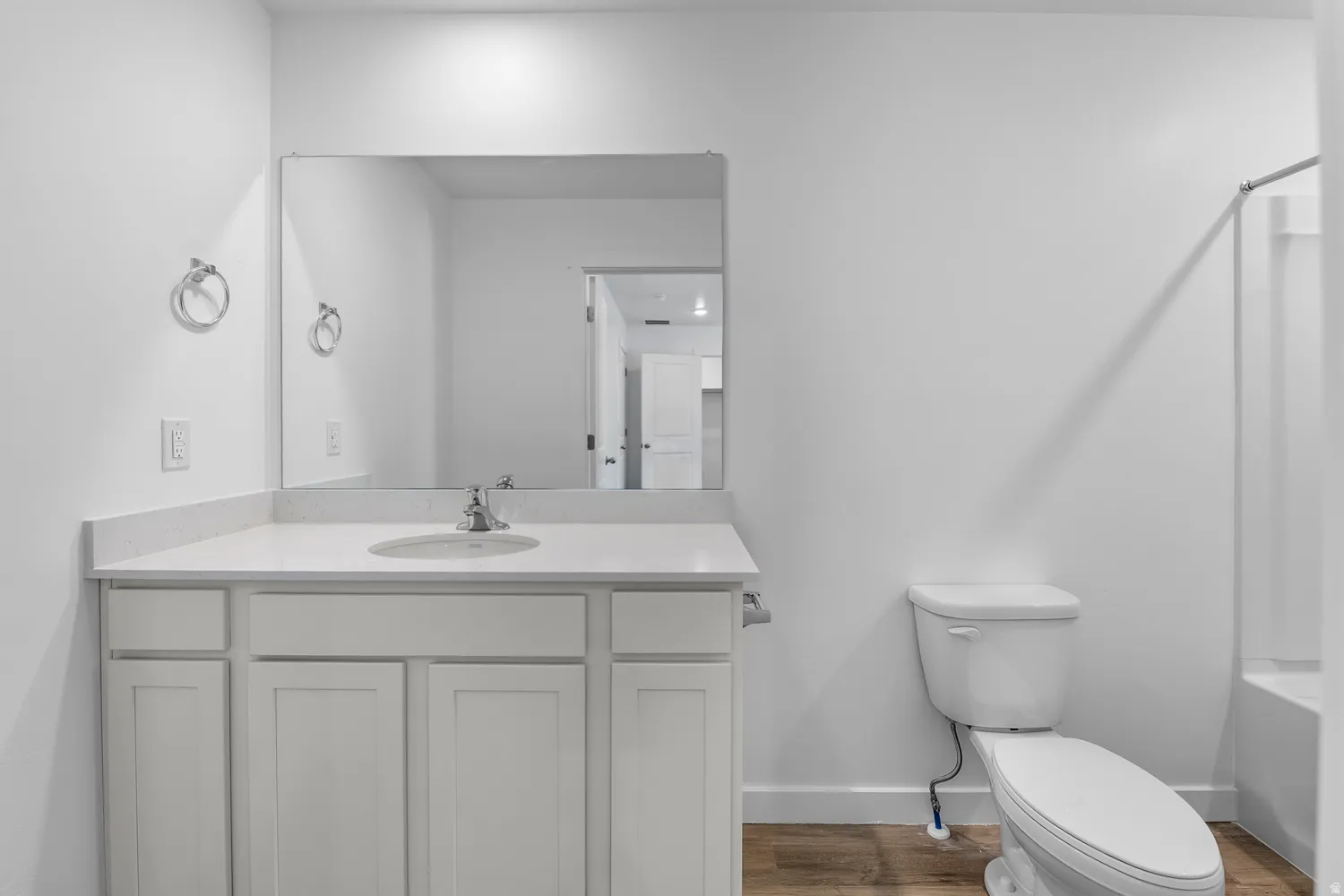 White shaker vanity with a light countertop, integrated sink, and chrome faucet