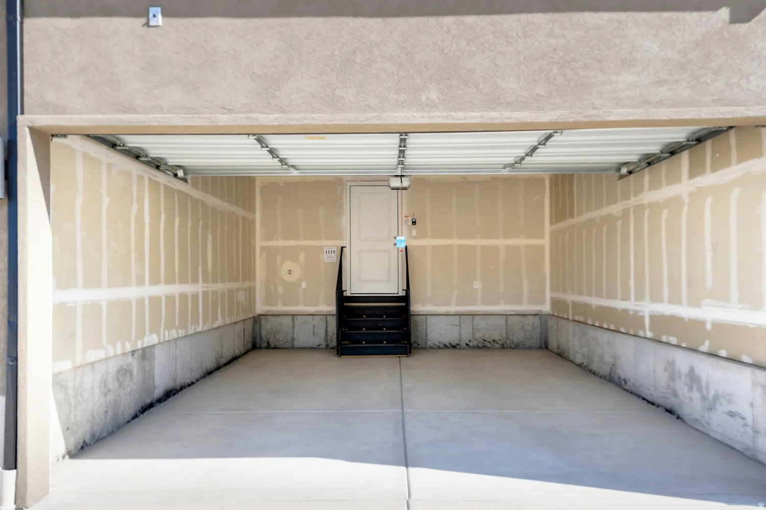 Spacious garage featuring a concrete floor, unpainted drywall walls, and a white interior door