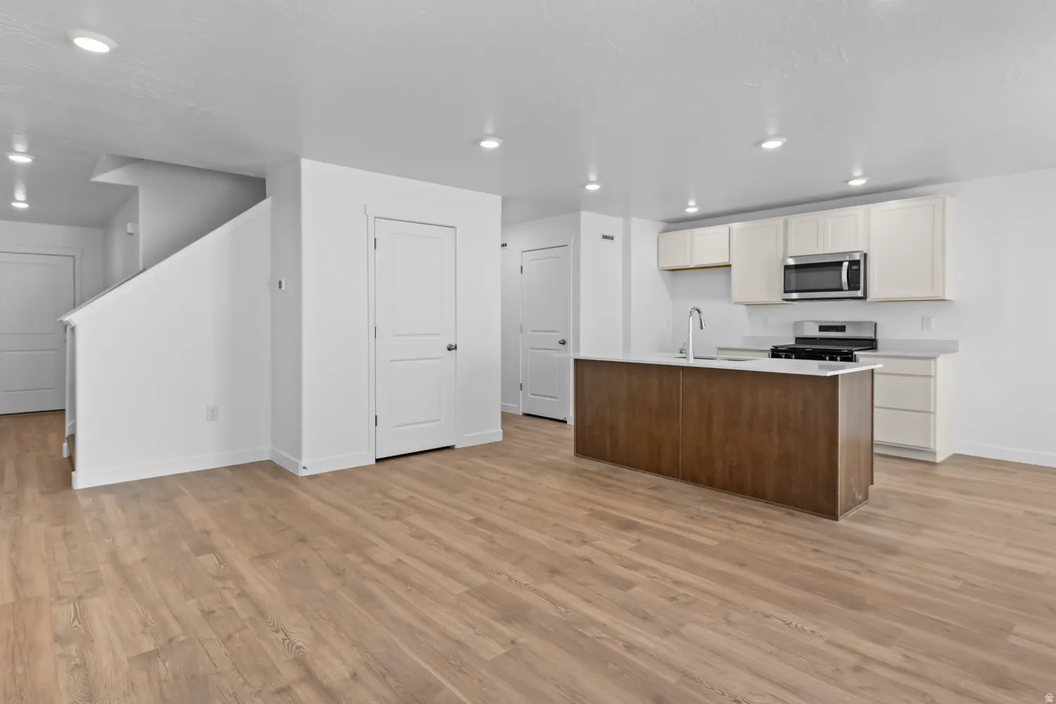 Open-concept living space featuring wood-finish flooring, recessed lighting, and a contemporary kitchen