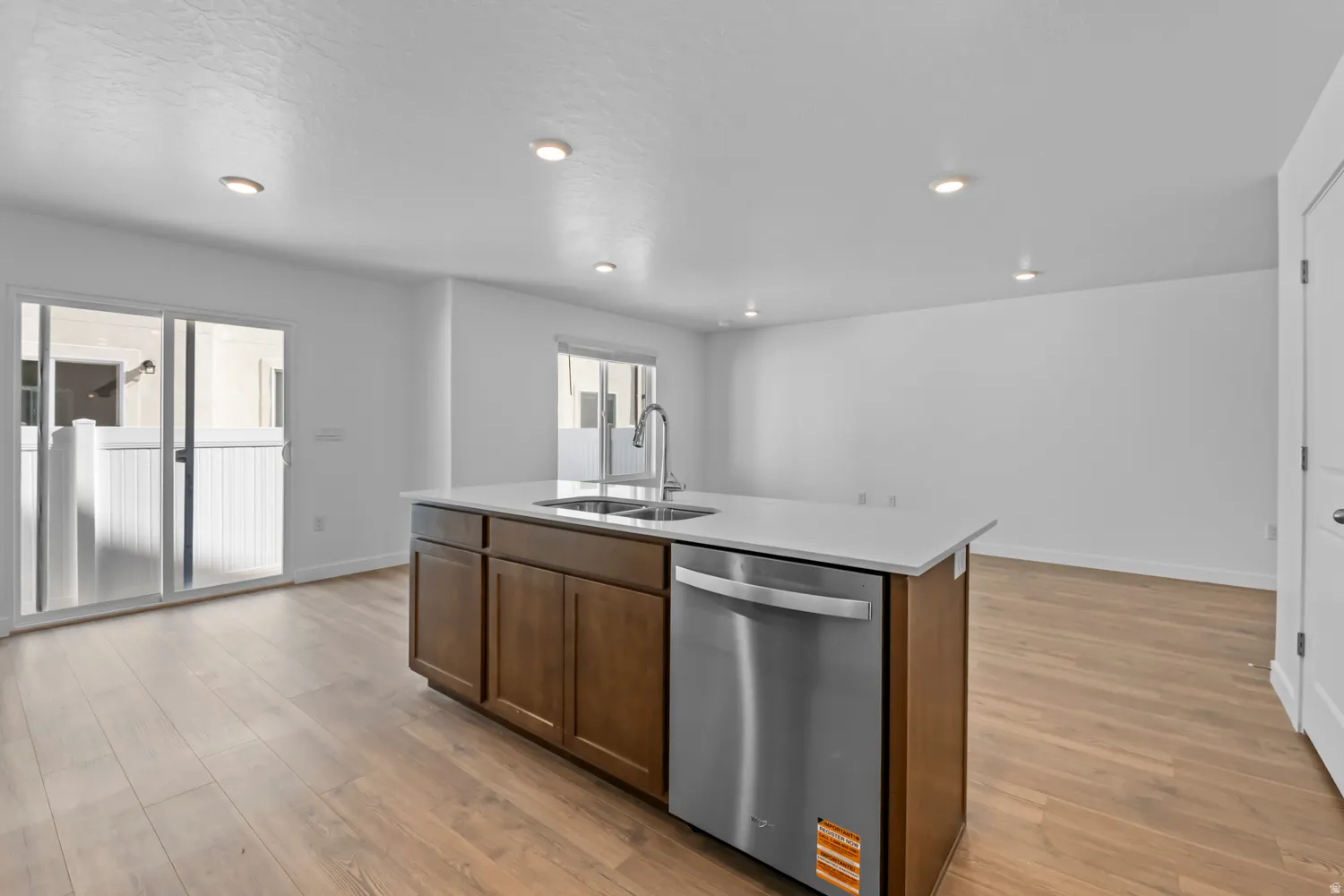 Kitchen island featuring a stainless steel sink, pull-down faucet, and integrated dishwasher