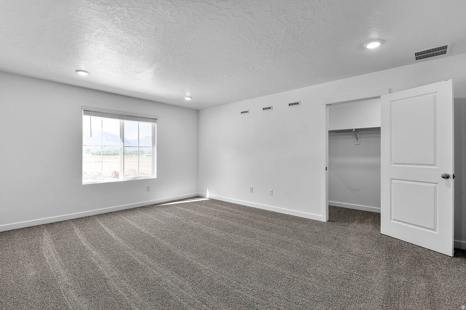 Spacious room with new gray carpeting, white walls, and recessed lighting