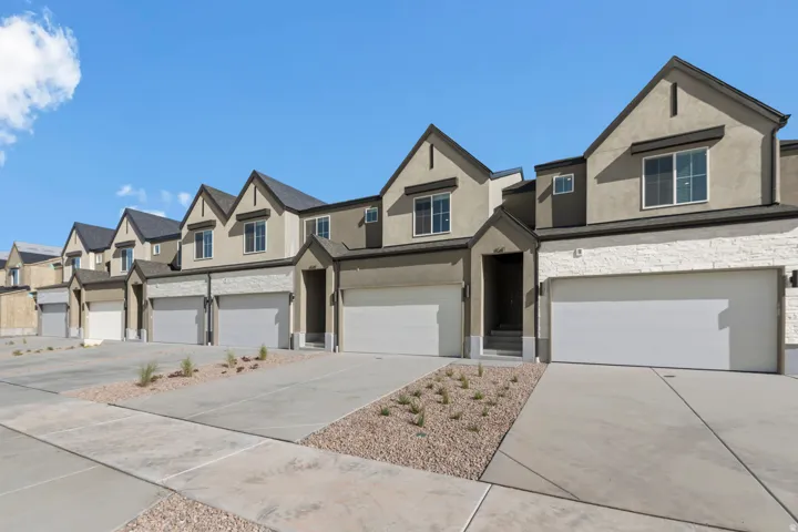 Row of townhomes featuring stucco exteriors, stone veneer accents, pitched roofs, attached garages, and concrete driveways