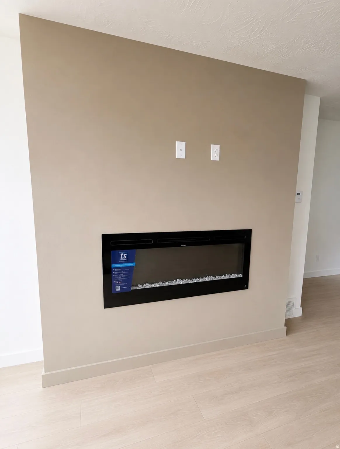 Built-in fireplace on a neutral-toned accent wall with light wood-finish flooring