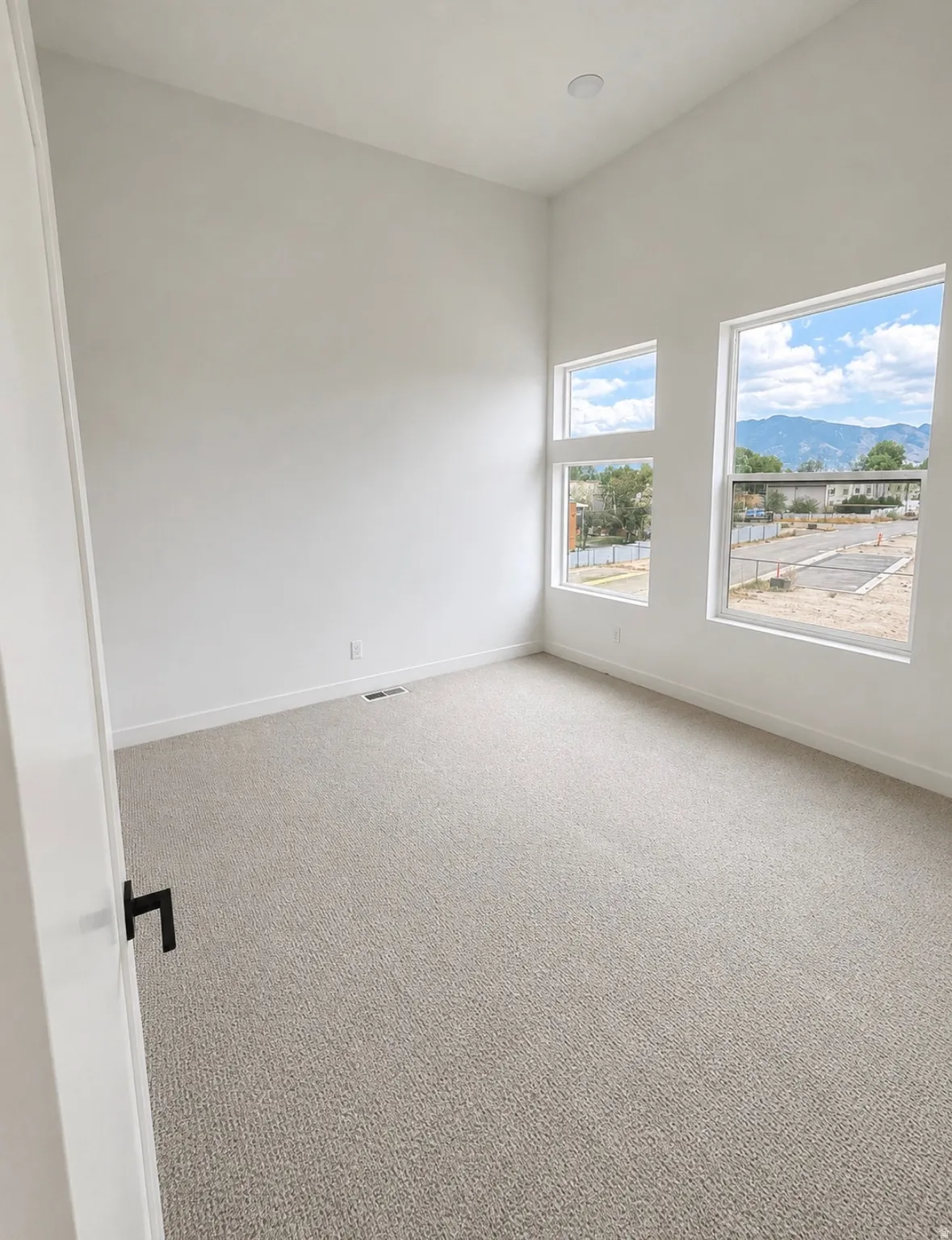 Bright room featuring white walls and neutral-toned carpet