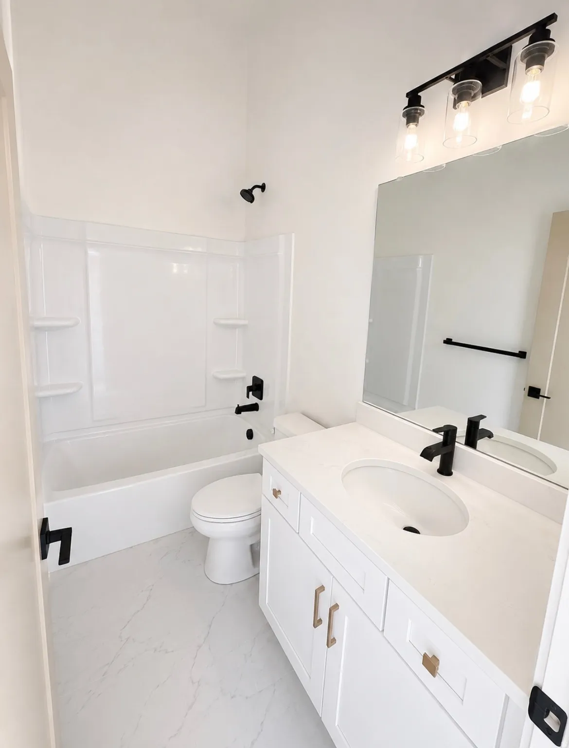 Bright bathroom featuring a white vanity with gold-tone hardware, a rectangular undermount sink, and a white countertop