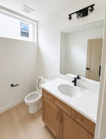 Bathroom featuring a wood-finish vanity with a white countertop, undermount sink, and matte black faucet