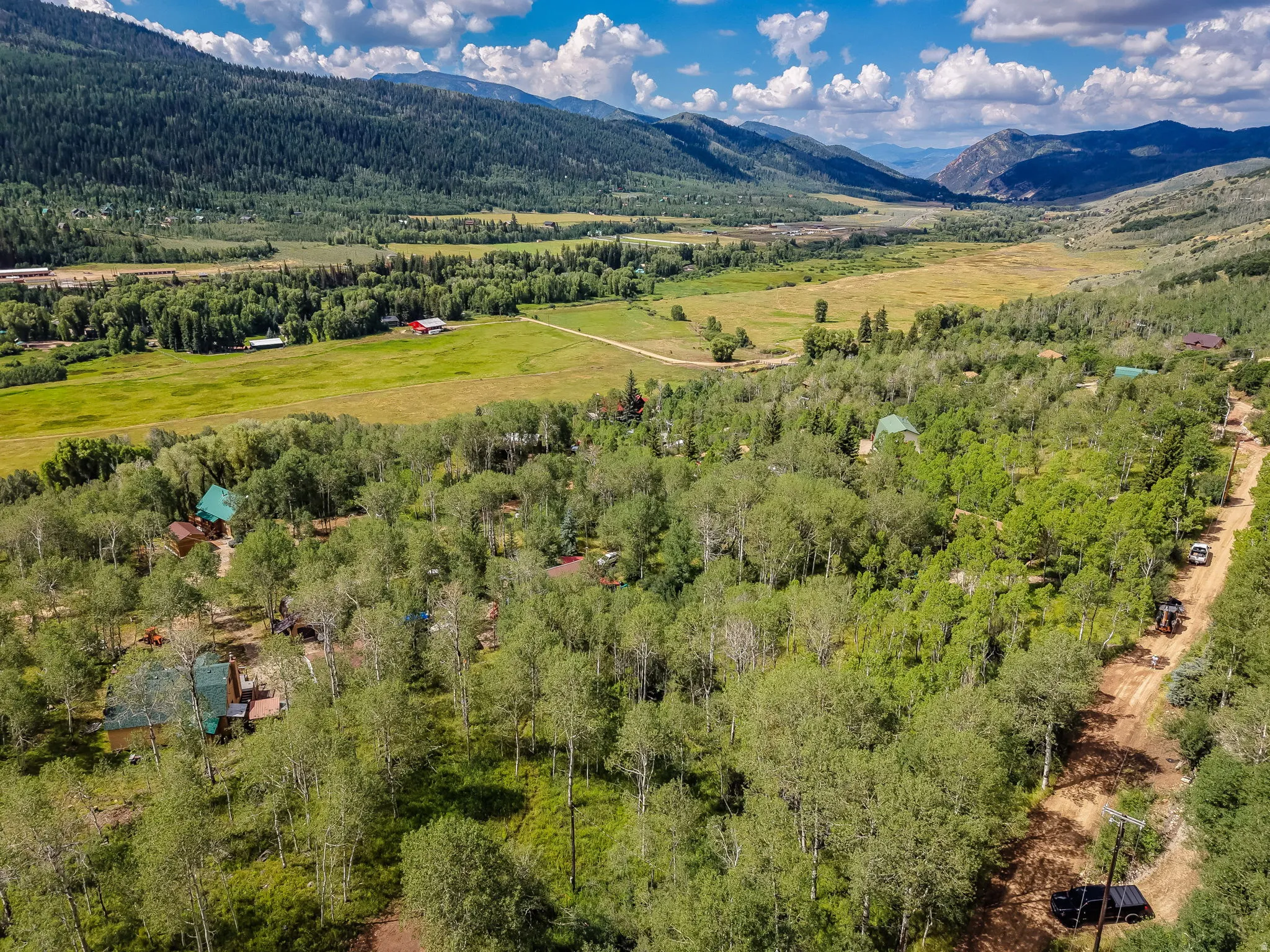 Expansive property featuring dense tree coverage, a natural landscape, and multiple structures