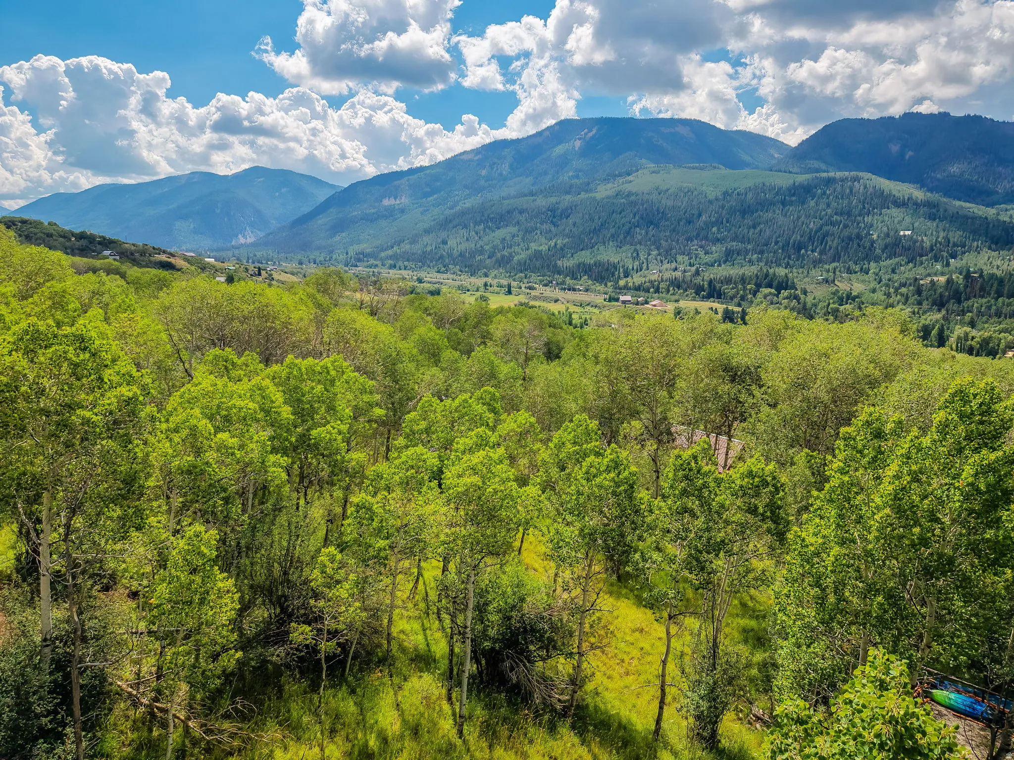 Mountain landscape featuring a valley with lush green trees and distant peaks