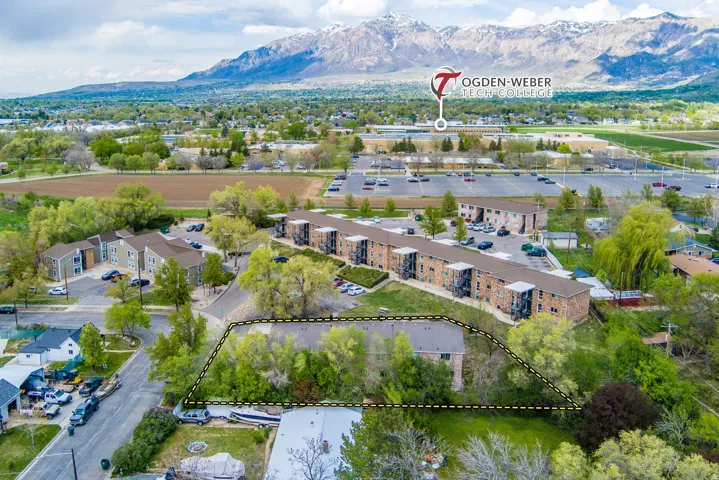 Aerial view showcasing a residential property outlined by a dashed line, surrounded by mature trees