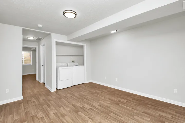 Laundry area with built-in shelving, wood-finish flooring, and recessed lighting