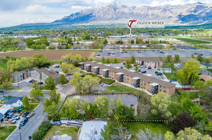 Multi-building property featuring brick and siding exteriors, mature landscaping, and ample surface parking