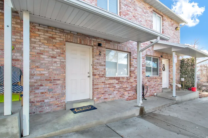 Brick exterior building with multiple entryways, each featuring a white paneled door and an overhead awning