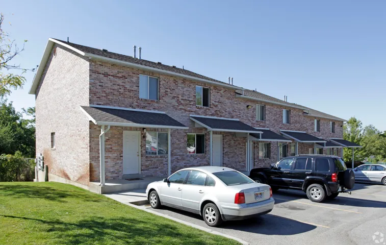 Brick exterior townhome with individual covered entryways, pitched shingle roof, and multiple windows
