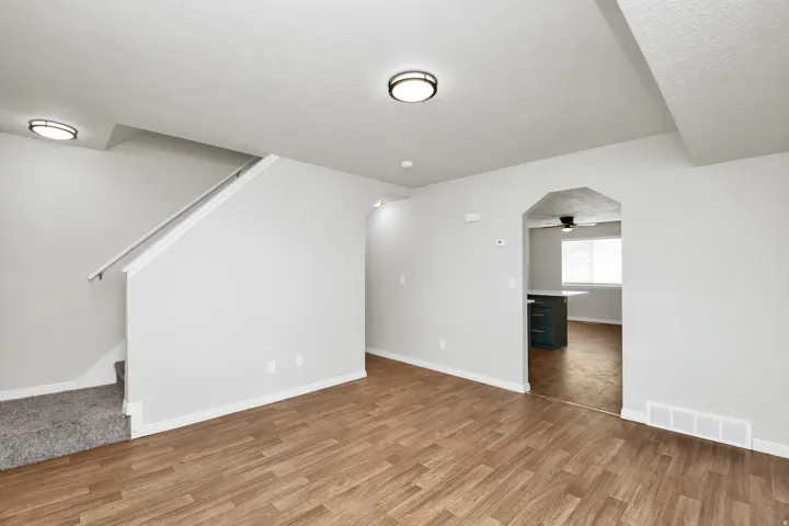 Spacious room with wood-finish flooring, light gray walls, and recessed lighting