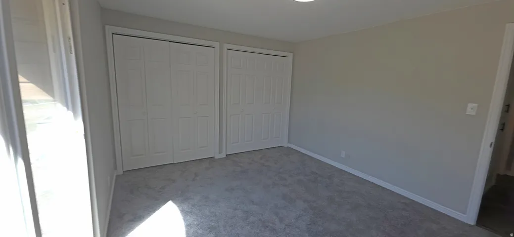 Carpeted room featuring two bi-fold door closets, recessed lighting, and a neutral wall color