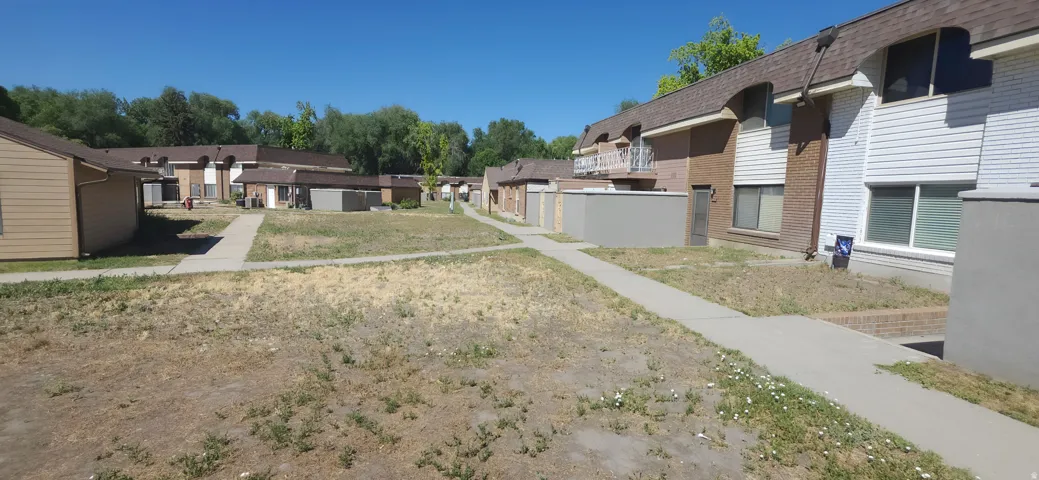 Multi-unit residential property featuring brick and siding exteriors, individual patios, and concrete walkways