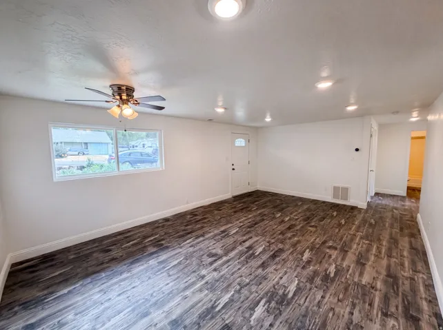 Spacious room featuring wood-finish flooring, recessed lighting, and a ceiling fan with light fixture