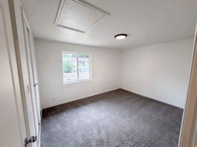 Spacious room featuring neutral paint, gray carpeting, a double window, and a flush-mount ceiling light