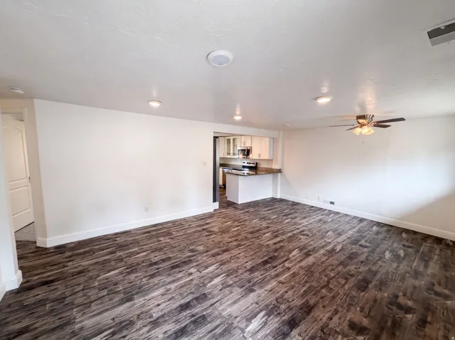Spacious room featuring wood-finish flooring, recessed lighting, and a ceiling fan
