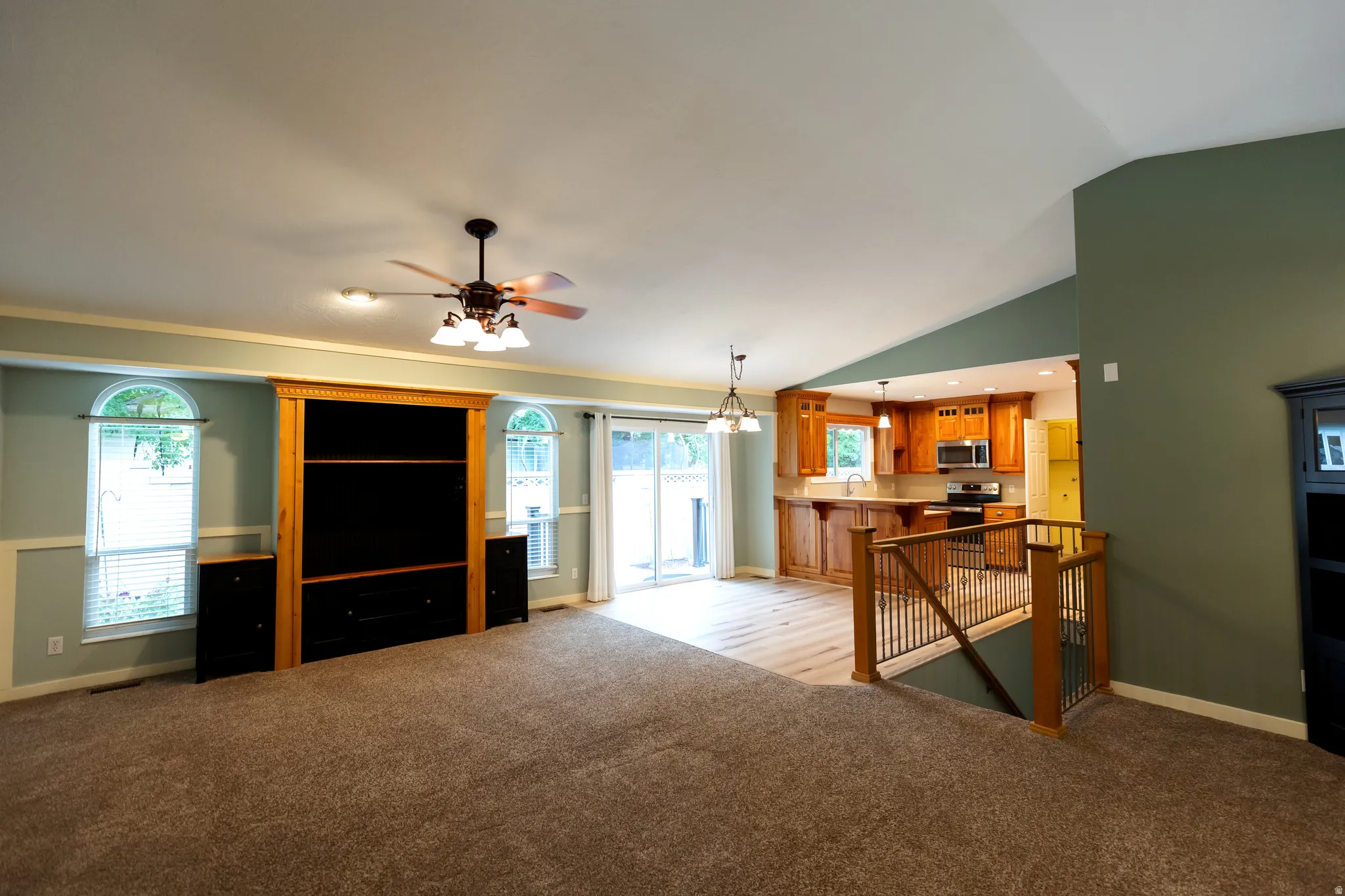 Spacious living area featuring carpet flooring, a built-in media center, and vaulted ceilings
