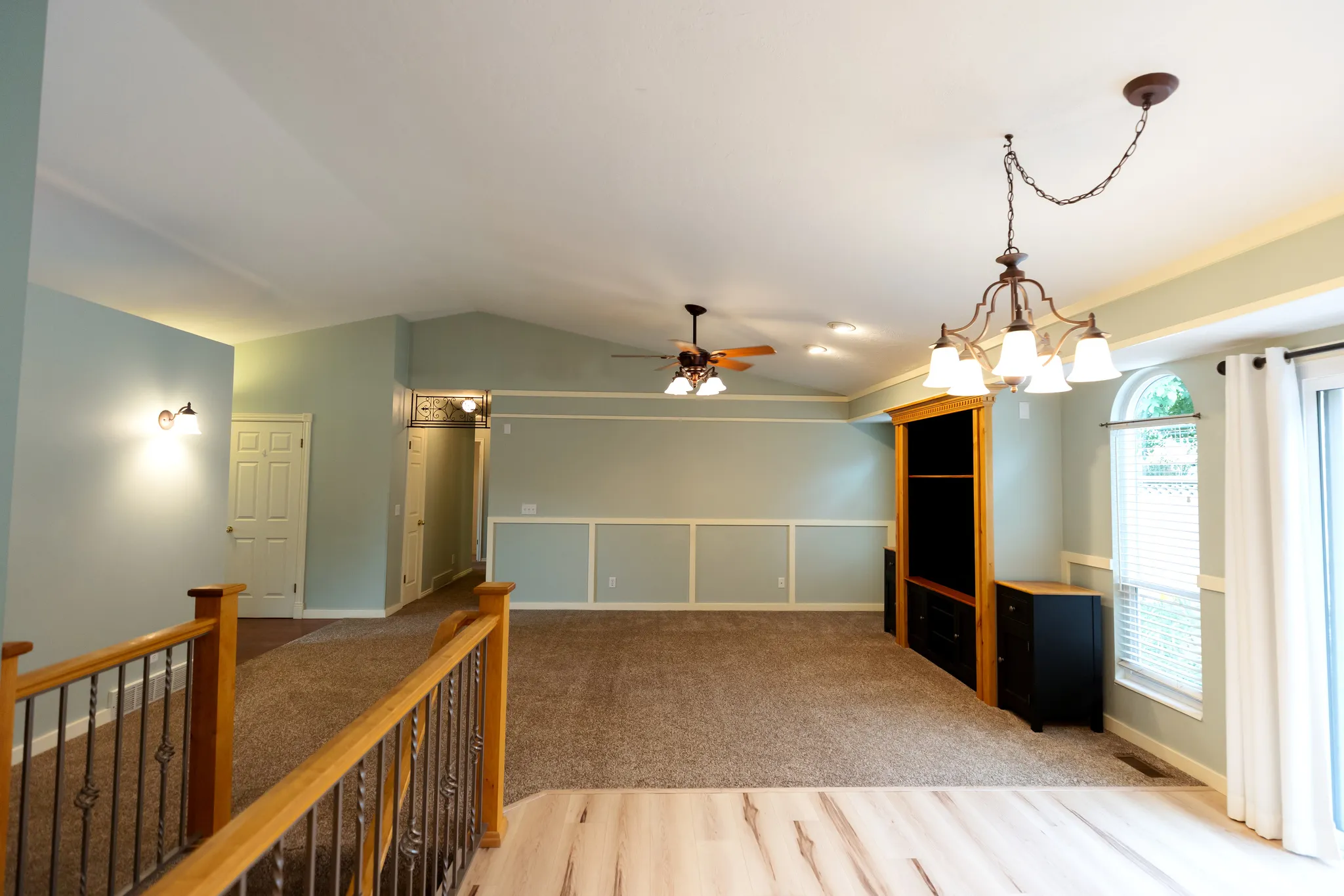 Spacious room featuring vaulted ceilings, a decorative chandelier, and a ceiling fan
