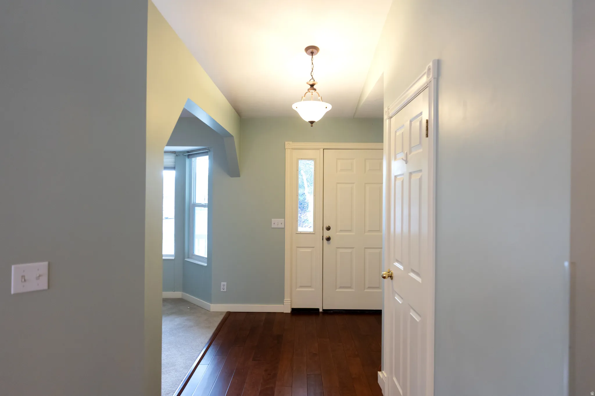 Entryway featuring wood-finish flooring, a paneled entry door with decorative glass, and a classic-style pendant light fixture