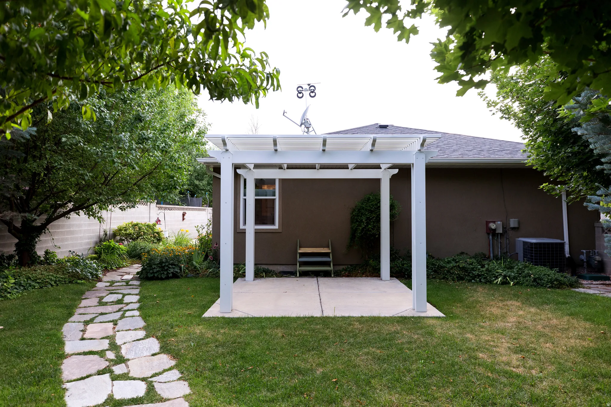 Backyard featuring a white pergola over a concrete patio