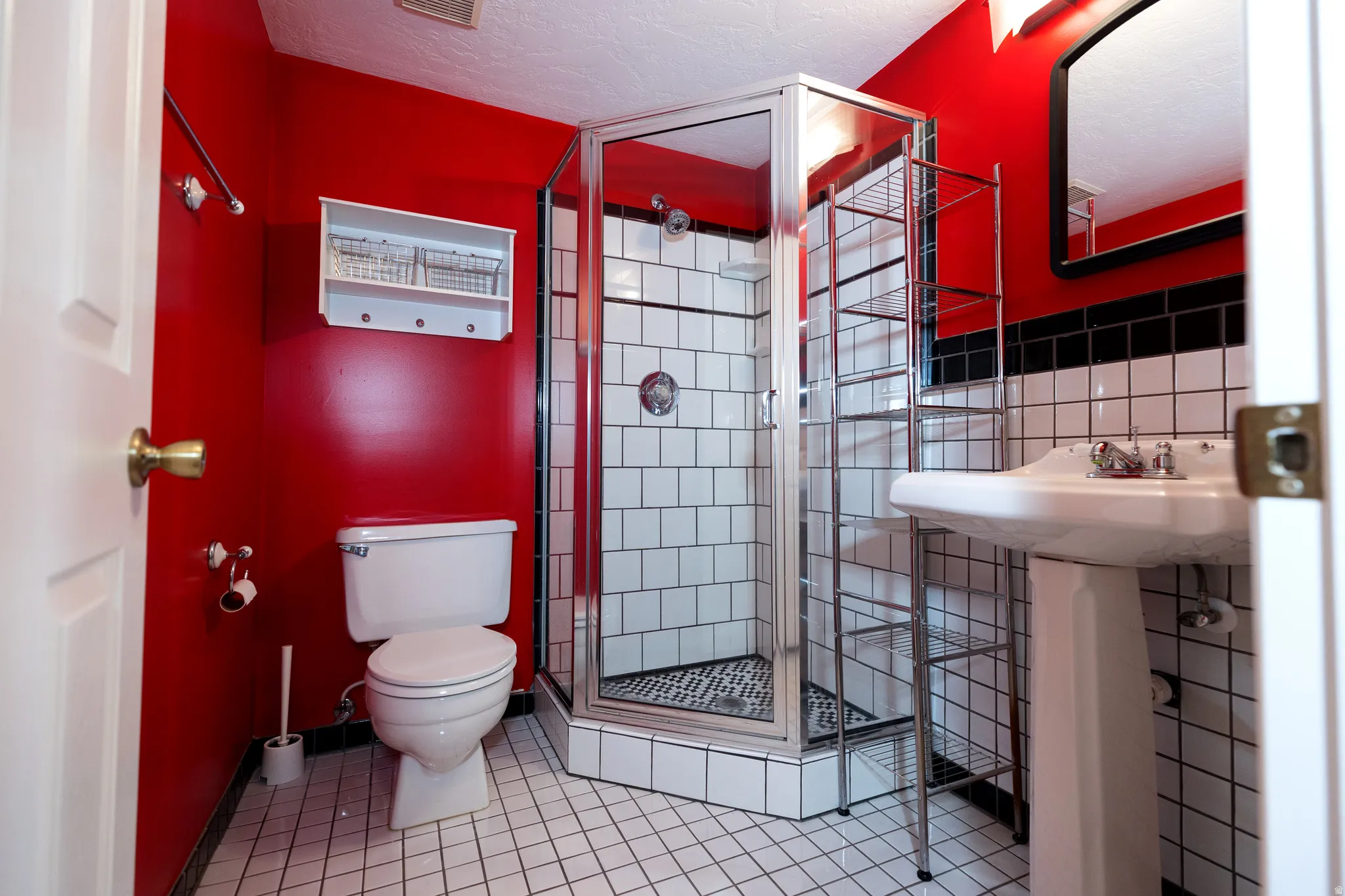 Bathroom featuring a glass-enclosed shower, pedestal sink, and white subway tile with dark grout