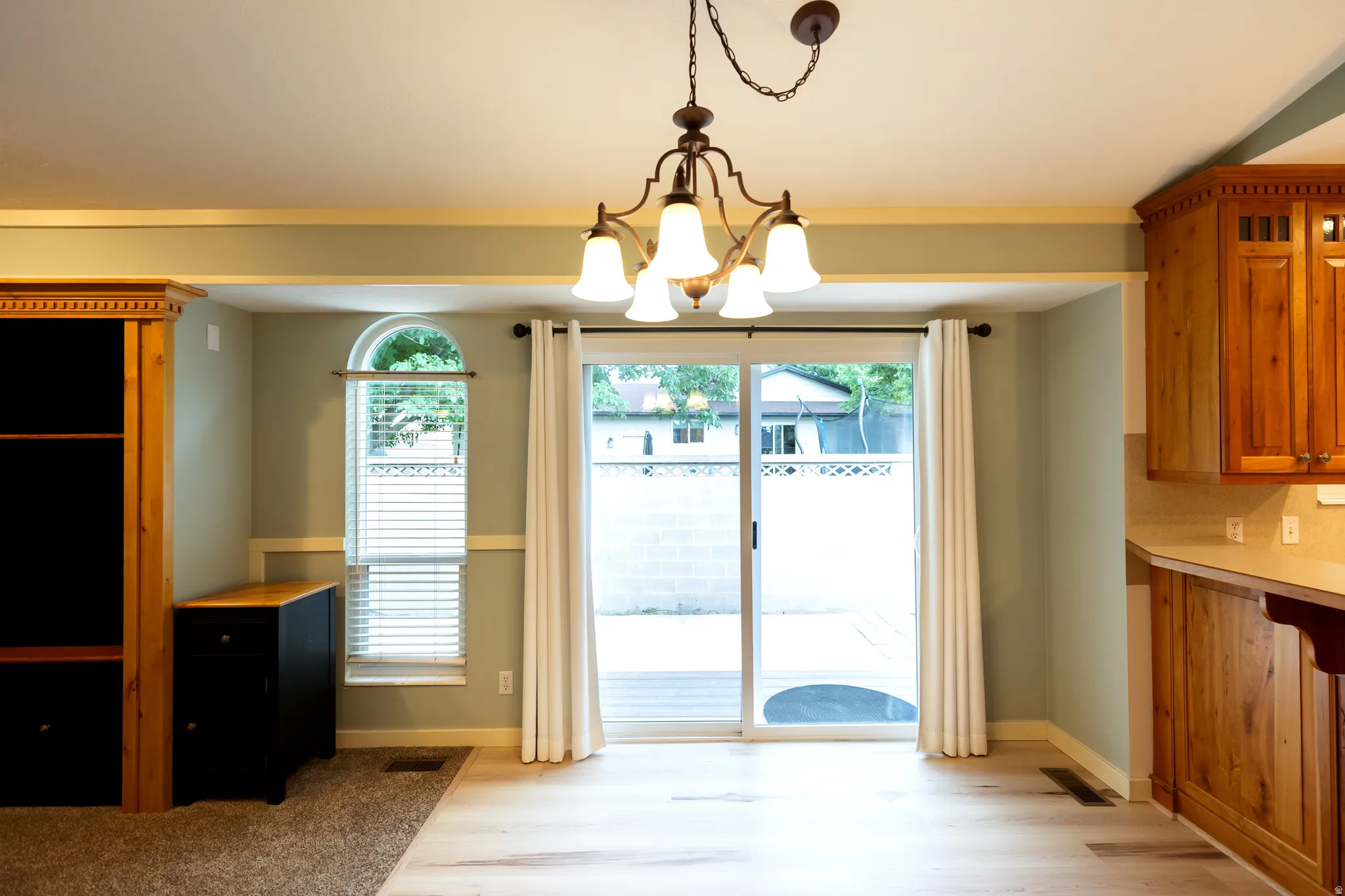 Dining area with a chandelier, light wood-finish flooring, and sliding glass doors opening to a patio