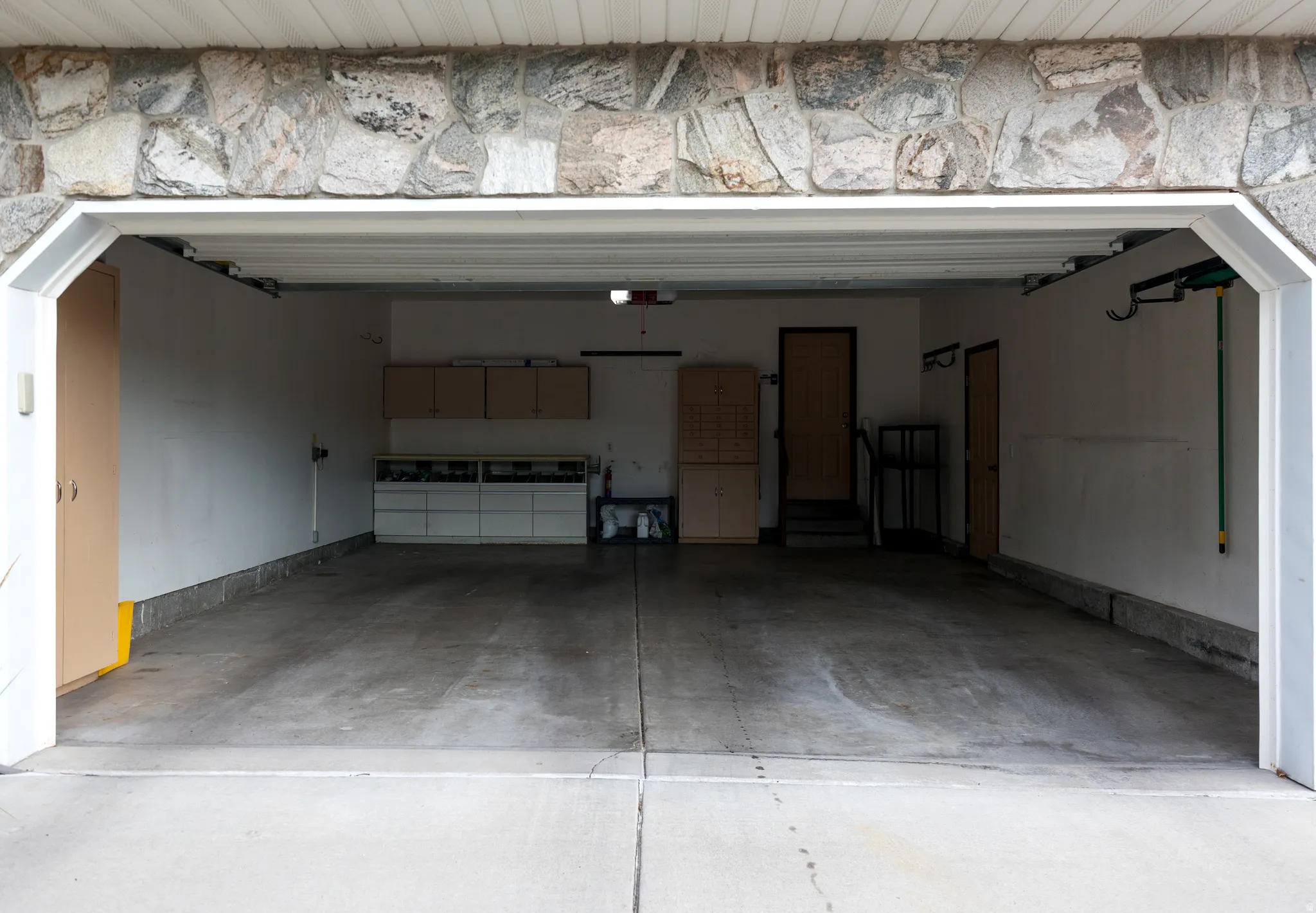 Two-car garage with concrete flooring and multiple storage options