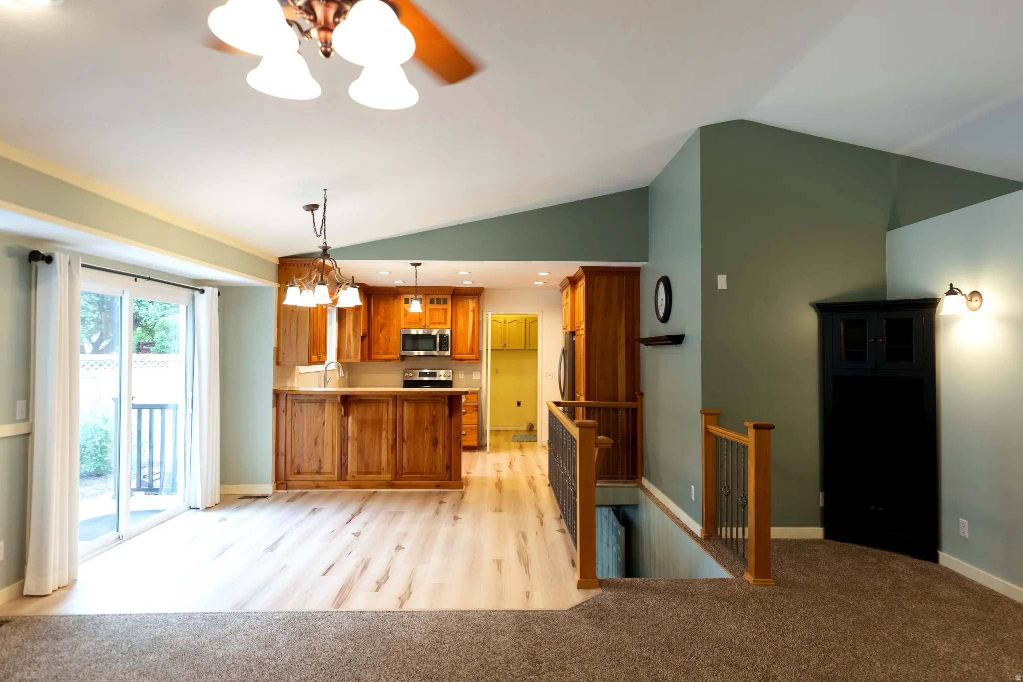 Open-concept living area with vaulted ceilings and a blend of carpet and wood-finish flooring