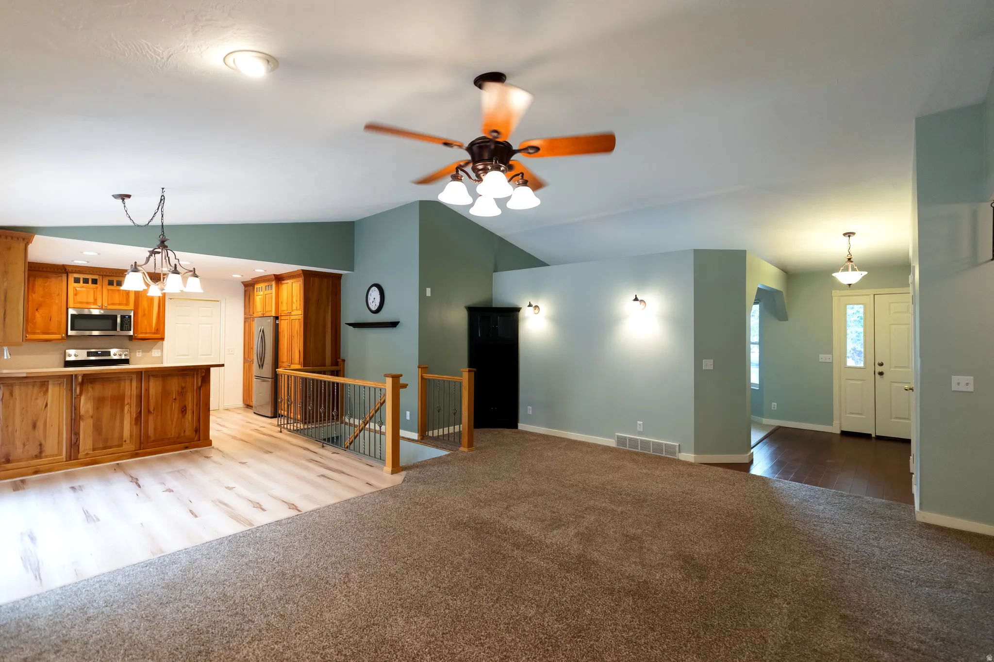 Open-concept living area featuring a kitchen with wood cabinetry, stainless steel appliances, and a central island