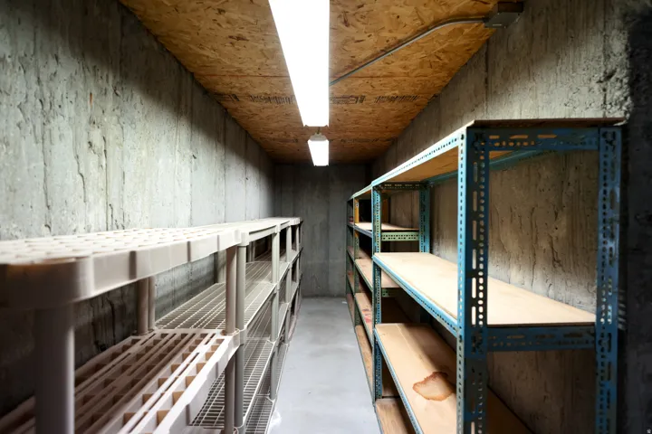 Dedicated storage room featuring concrete walls, a plywood ceiling, and two fluorescent light fixtures