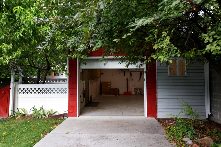 Attached garage with a concrete driveway, red and gray siding, and a white lattice fence