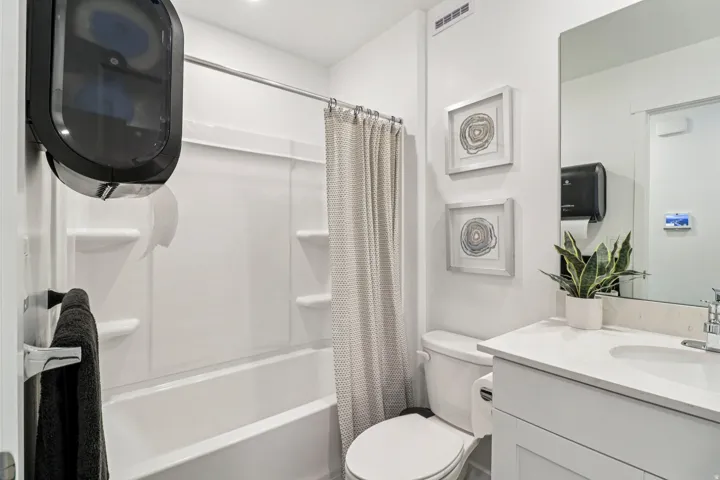 Bathroom featuring a white vanity with an integrated sink, a large wall-mounted mirror, and a toilet
